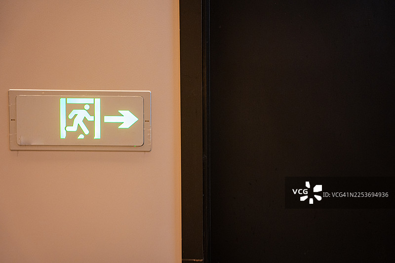 灰色的墙壁上有一个绿色的紧急出口标志图片素材