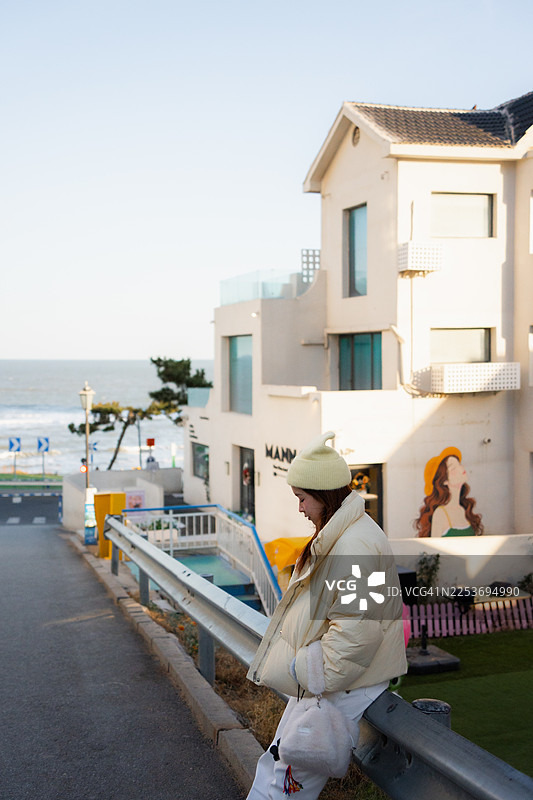 年轻女子沿着海边的街道行走图片素材