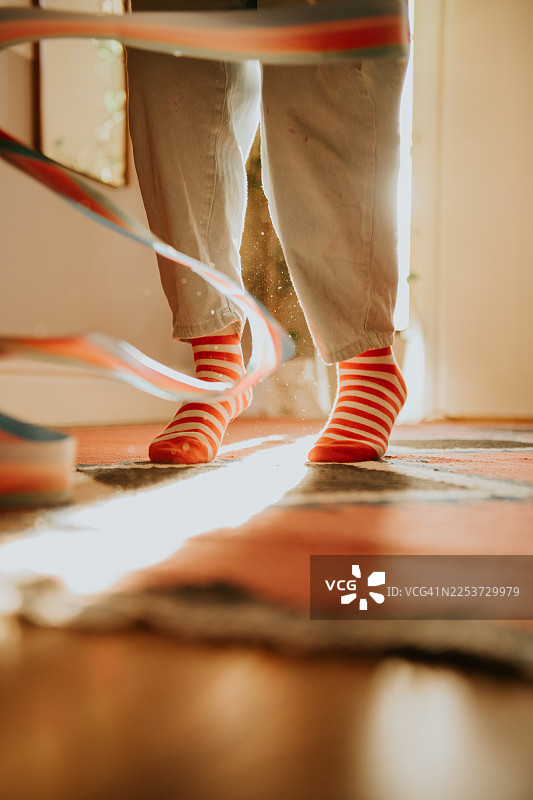 一个孩子在时尚、居家、阳光明媚的环境中玩彩带棒，专注于她穿着条纹袜的小脚。图片素材