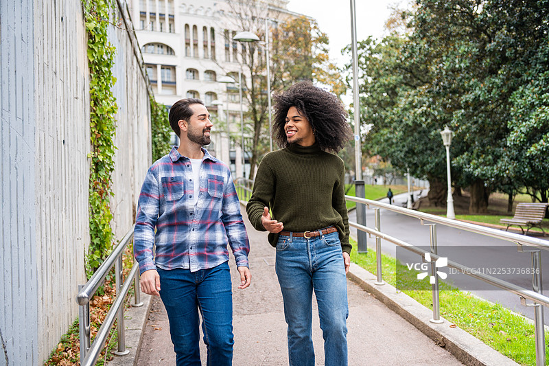 两个男性朋友在城市公园里边走边聊图片素材