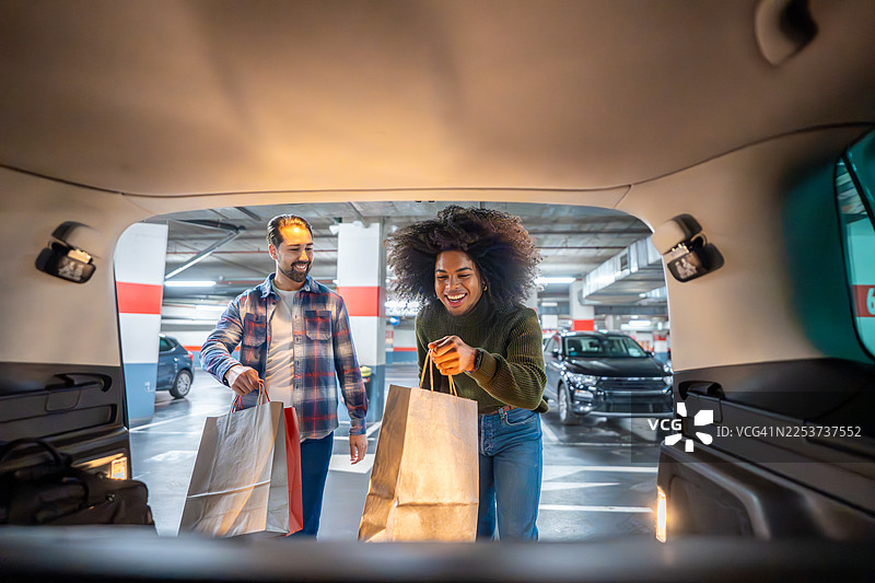 开心的朋友们把购物袋装进汽车后备箱图片素材