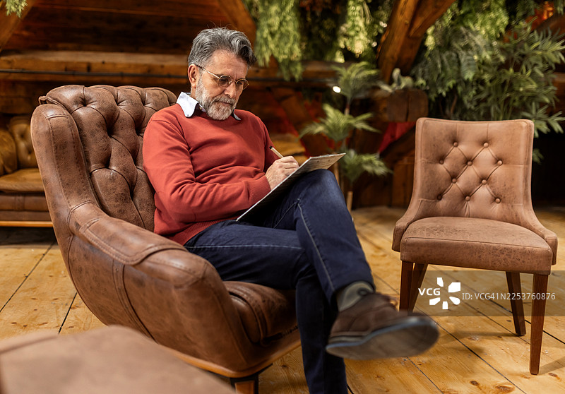 一位年长男性在舒适的室内环境中等待情感支持小组的会议图片素材