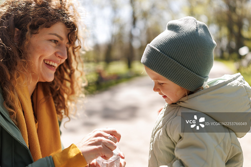 口渴的可爱小女孩在阳光明媚的公园里喝水图片素材