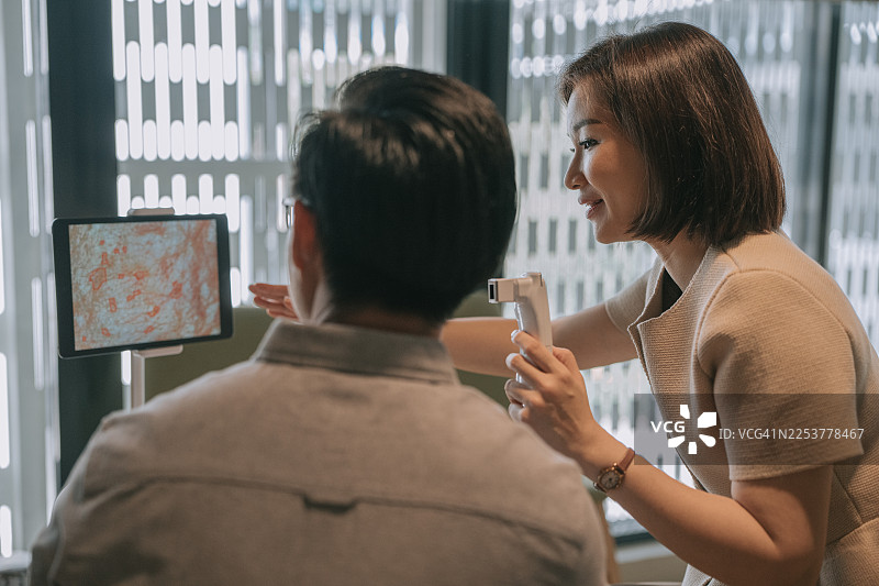 亚洲的皮肤护理顾问向男性客户解释皮肤分析结果图片素材