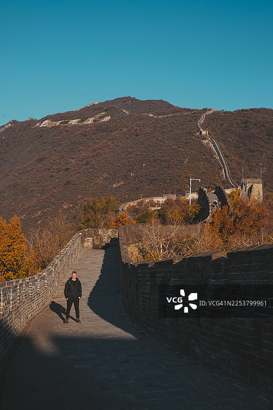 秋日群山中，孤独的旅人走在长城上的剪影图片素材