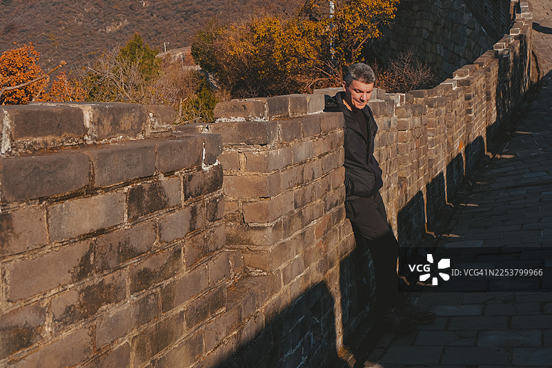 秋日落时分，一位孤独的游客倚靠在中国长城上图片素材