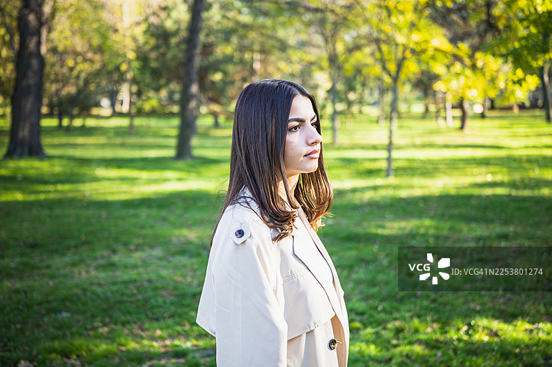 秋日晴天，一位身穿外套的美丽年轻女子在公共公园享受咖啡休息的肖像。图片素材