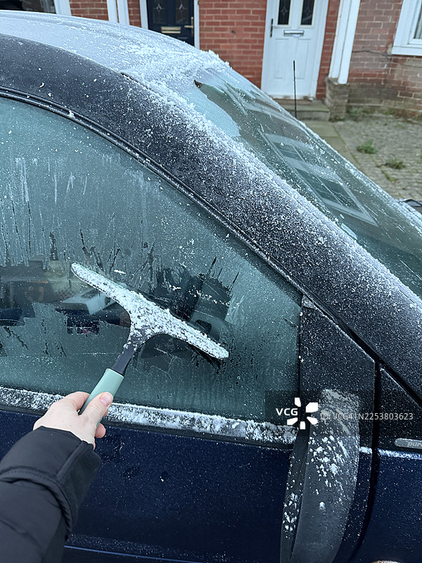 在冬日清晨用刮刀清除结冰的车窗图片素材