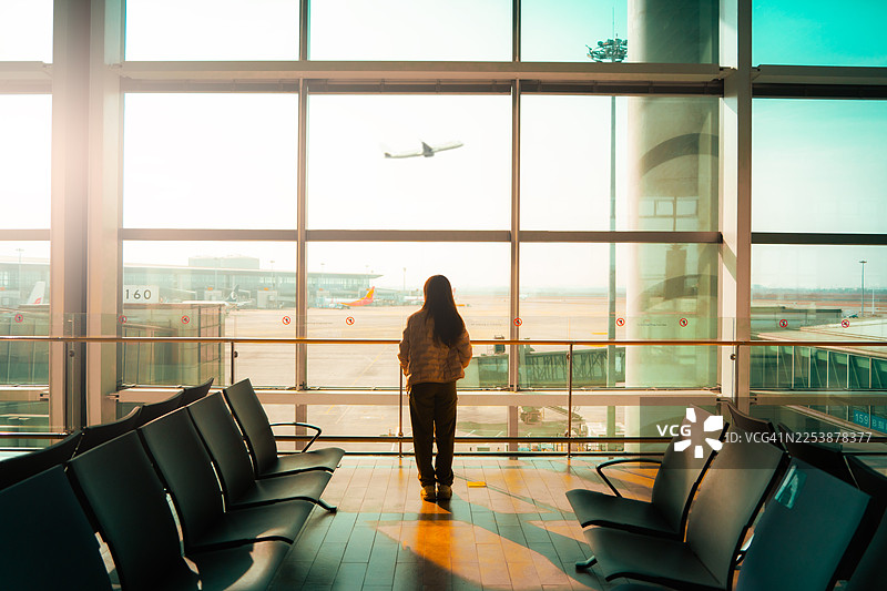 年轻亚裔女性在机场用智能手机查看航班时刻表图片素材