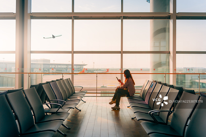 年轻的亚洲女性在机场用智能手机查看航班时刻表图片素材