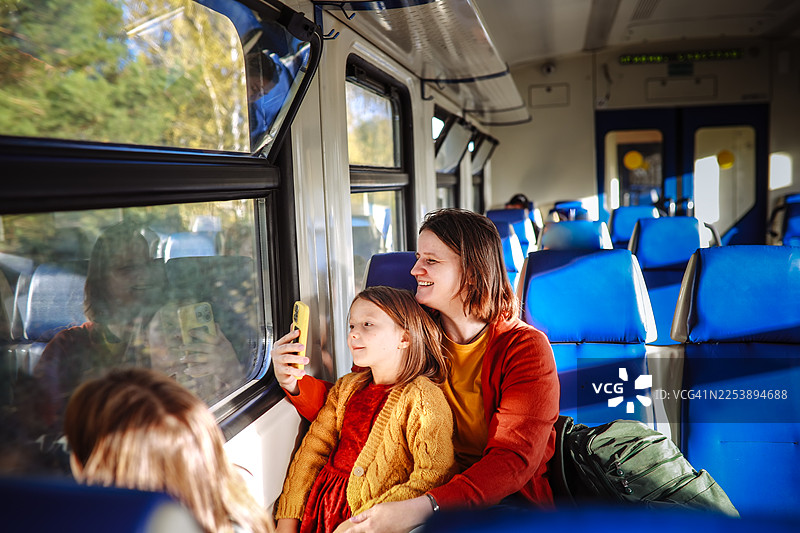 家庭旅行——母女俩在洒满温暖灯光的火车上图片素材