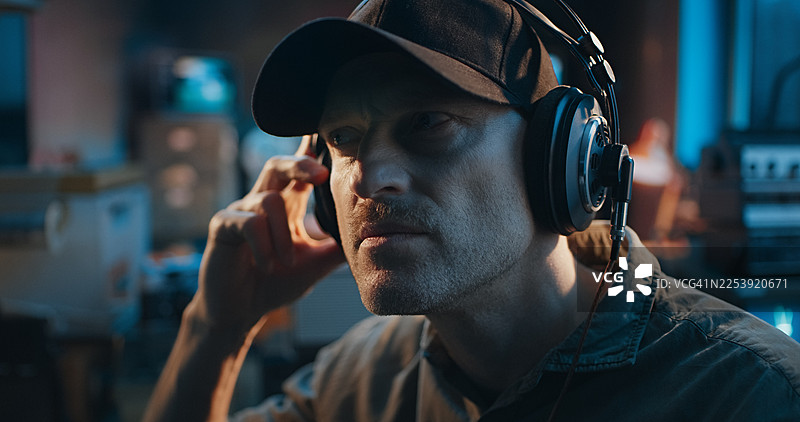 佩戴着大耳机、正在通过收音机接收新闻或数据的无线电操作员。特写肖像。业余无线电台图片素材