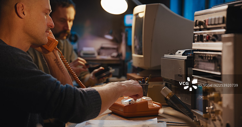 安全房间内的复古无线电通讯。两位操作员正在用软盘整理数据并接听固定电话。秘密调查记者工作图片素材