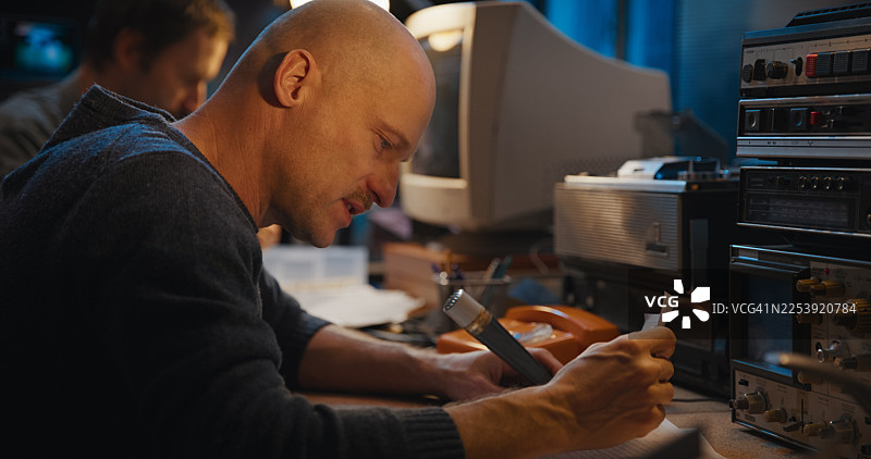 复古无线电通信设备在一个安全房间内。两名操作员通过无线电发送信息，并抄写对话记录。秘密调查新闻报道图片素材