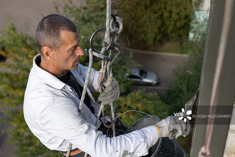 建筑工人在高处为房屋外墙进行隔热施工。图片素材
