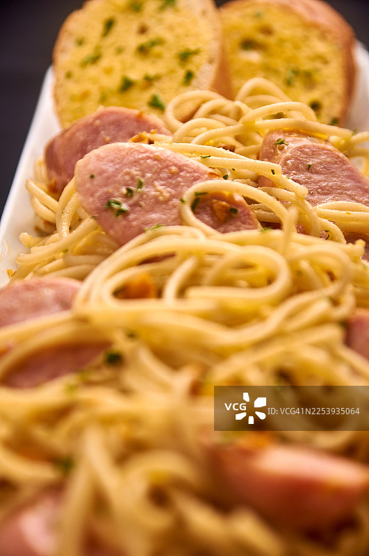 金黄蒜片和切碎香草的香肠意面特写图片素材