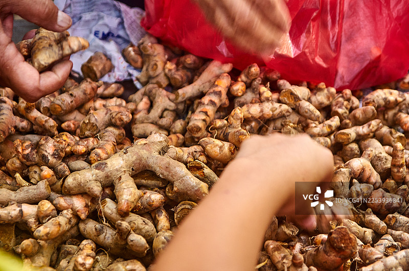 当地市场上一堆新鲜的姜黄根，色彩鲜艳。图片素材