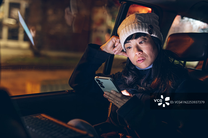 夜晚，一名女子在车内忧虑地看着智能手机图片素材