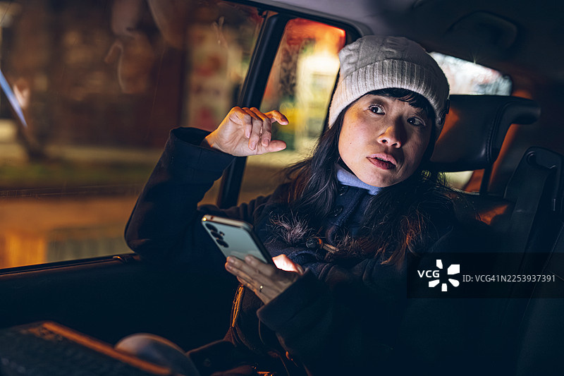 夜晚，一名女子在车内担忧地看着手机图片素材