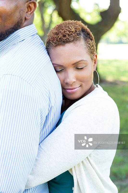 年轻情侣在温暖的户外光线下深情拥抱。图片素材