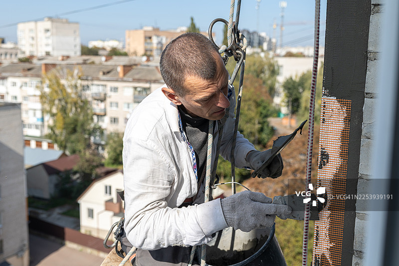 建筑工人在高处为房屋外墙保温图片素材