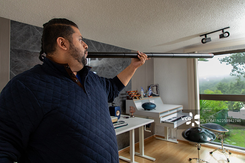 男人在家庭音乐工作室演奏迪吉里杜管，创作音乐并探索乐器图片素材