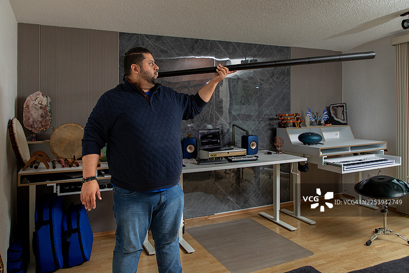 男性音乐家在家里的录音室演奏原住民迪吉里杜管，用各种乐器制作民族音乐图片素材