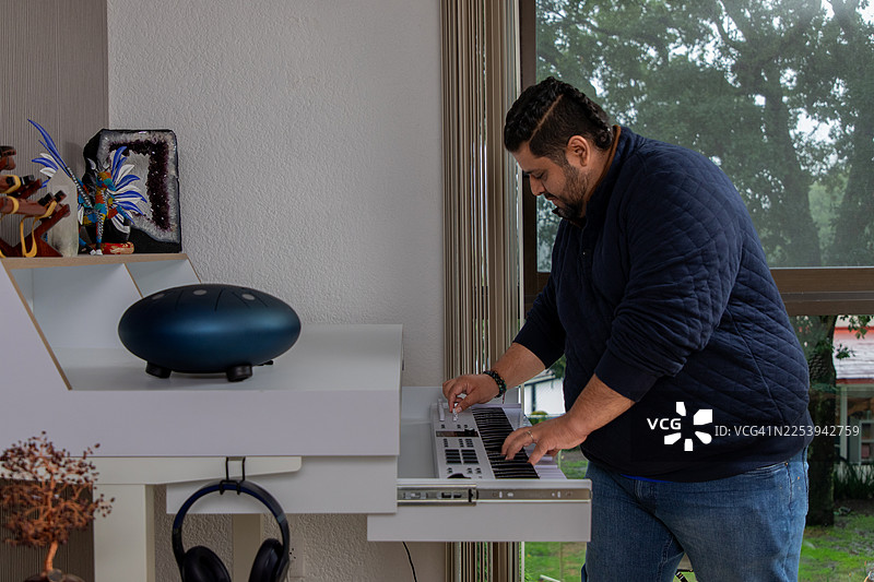 音乐家在家中工作室使用MIDI键盘和合成器创作电子音乐，创造新声音图片素材