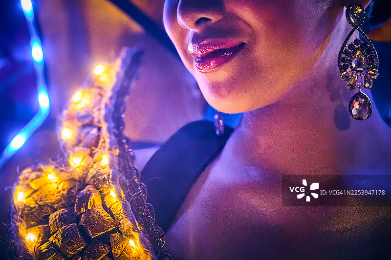 一名节日参与者身着装饰有多彩、抽象和自然图案的大型发光服装，背景是黑暗的夜空。图片素材