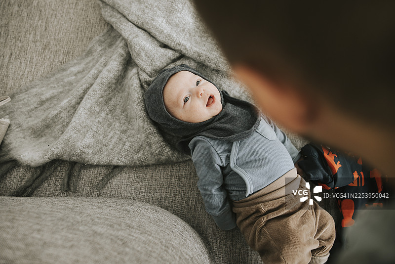 俯视视角，一个顽皮的蹒跚学步的男孩躺在沙发上图片素材