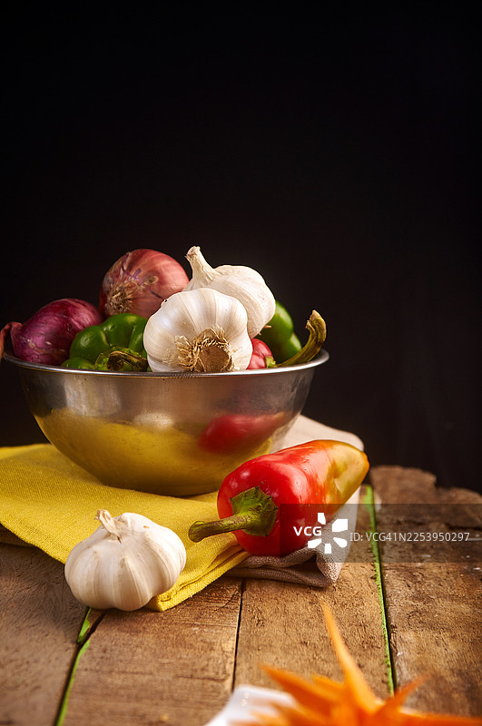 深色背景下，木质表面上展示着质朴的新鲜蔬菜。图片素材