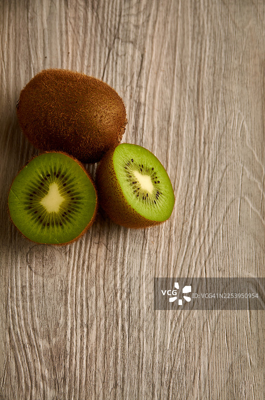 浅色木质表面上三个猕猴桃的俯视图。图片素材