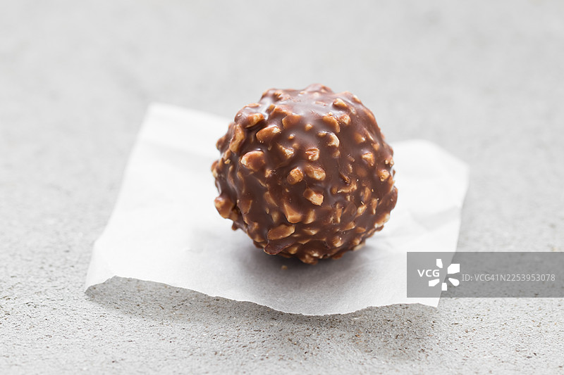 包含果仁糖和榛子的糖果球。外面裹着一层碎榛子牛奶巧克力。浅灰色背景。特写。图片素材