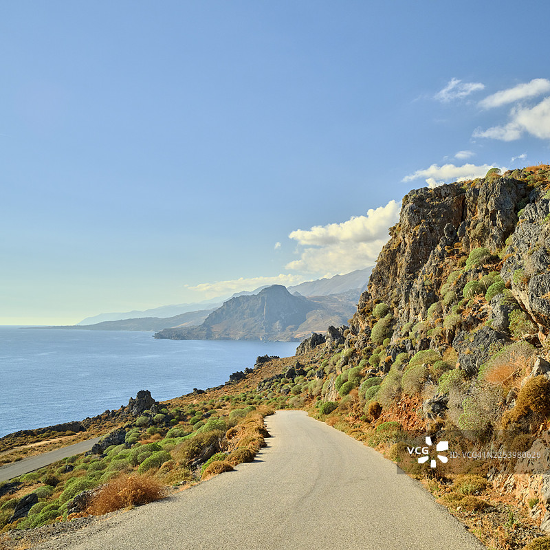 克里特岛的奇幻自然风光：希腊，沿着崎岖悬崖蜿蜒的海岸公路，伴随着湛蓝大海和明媚天空图片素材