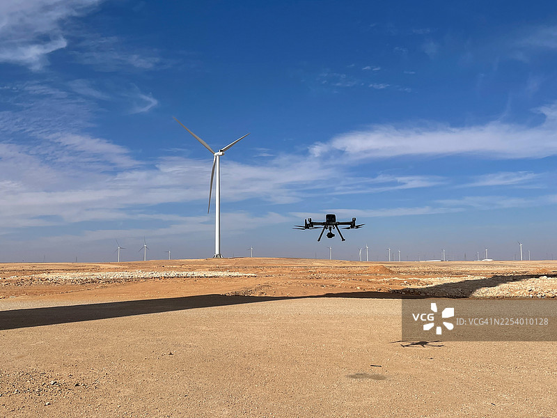 一架工业无人机正在沙特阿拉伯乡村的风力涡轮机农场上空盘旋图片素材