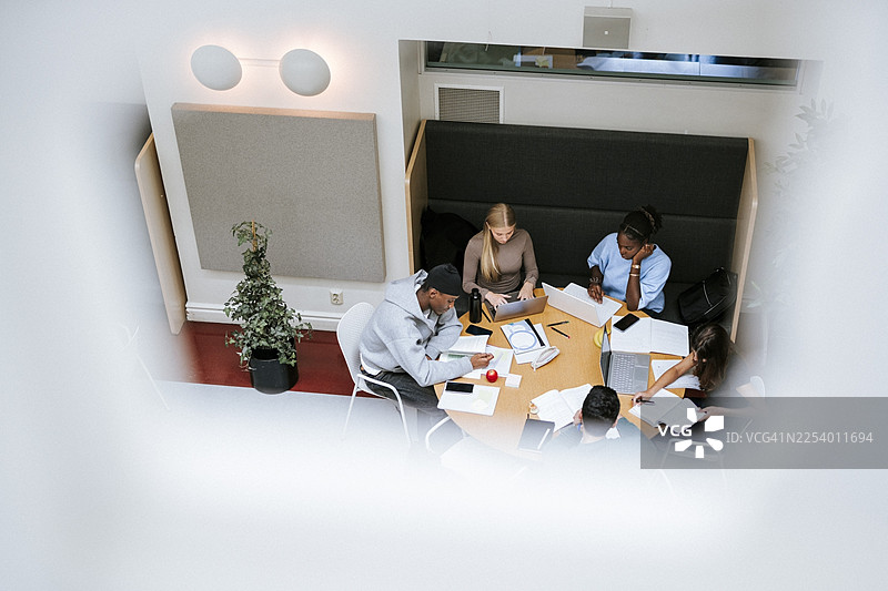 高角度拍摄的男生和女生在大学校园里坐着一起学习的专注场景图片素材