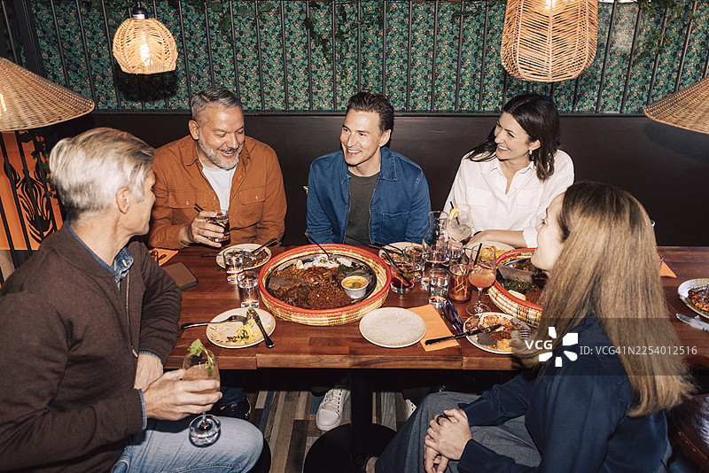 俯视视角下，朋友们在灯火通明的餐厅里享用晚餐派对图片素材