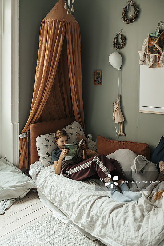 俯视角度拍摄的女孩在家中躺在沙发上看书的画面图片素材