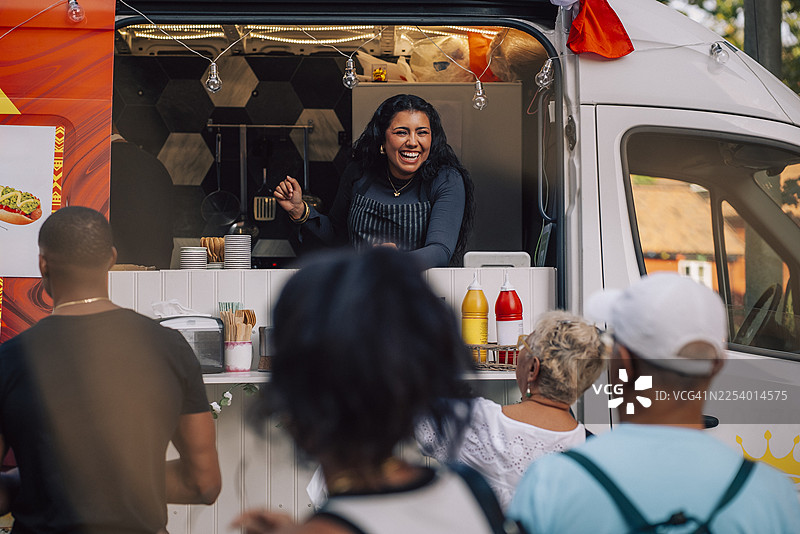快乐的年轻女老板在餐车前与顾客交谈图片素材