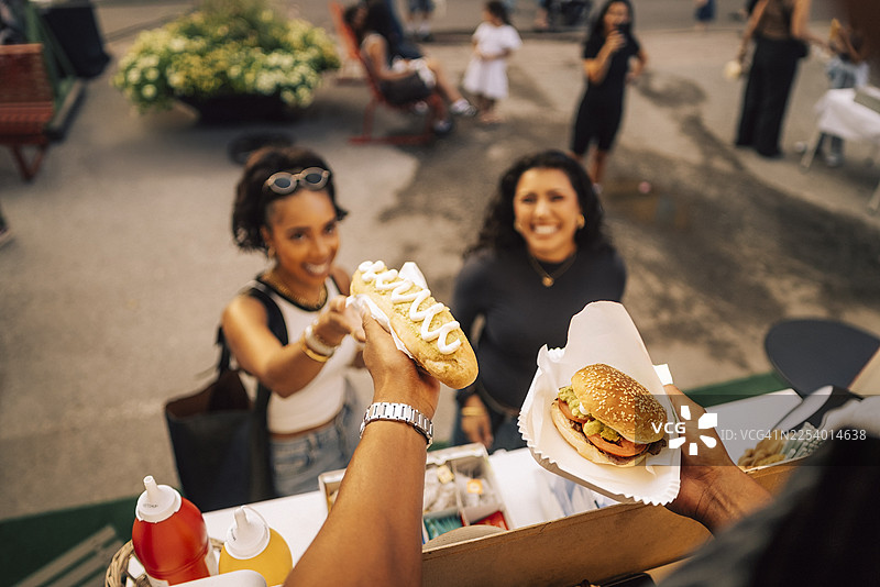 从高处俯瞰食品餐车上的销售员递给顾客热狗和汉堡图片素材
