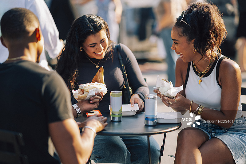 快乐的女人与朋友们一起在桌边享用快餐图片素材