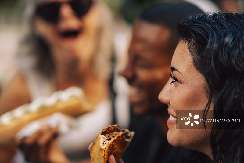 年轻女子与朋友们一起享用开胃菜，脸上带着笑容图片素材