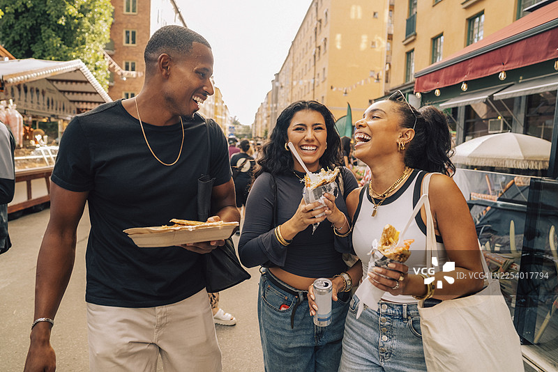 无忧无虑的男性和女性朋友在美食节上享用开胃菜图片素材