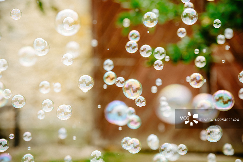 夏日阳光下漂浮的彩虹色肥皂泡，明亮自然光中的魔法彩虹倒影图片素材