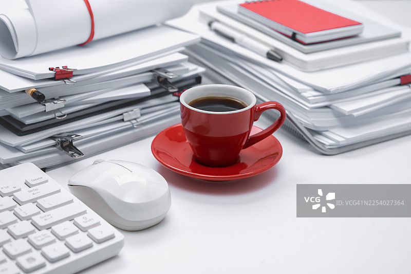 办公桌上的白色文具，充满文件堆的办公室氛围，空白笔记本和红色咖啡杯。图片素材