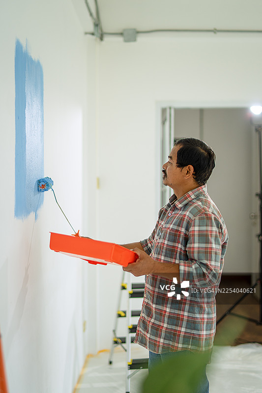 画家正在粉刷房子的墙壁。图片素材