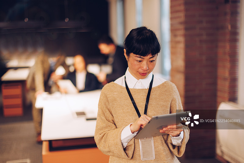 亚洲女商人在现代办公室里使用数字平板电脑图片素材