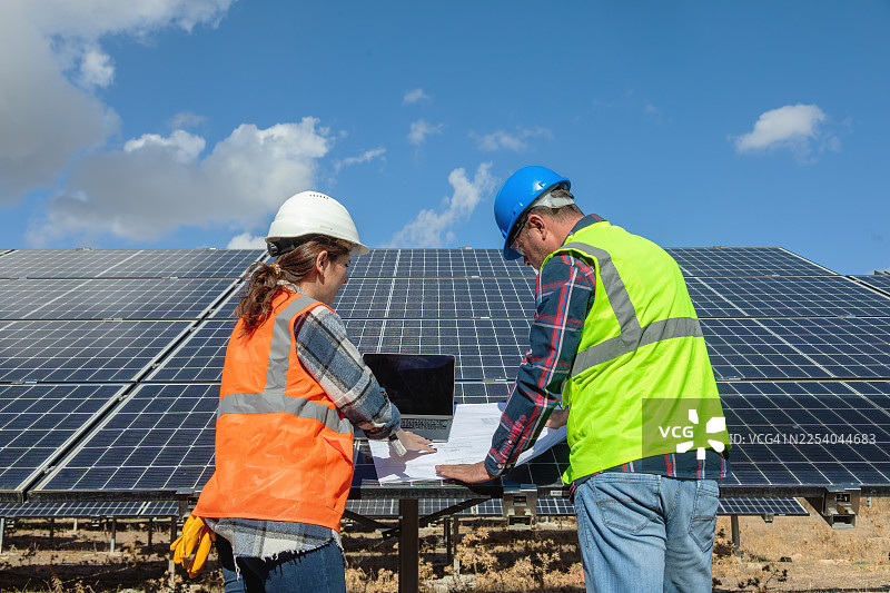 太阳能工程师和技术人员在可再生能源发电厂检查光伏太阳能电池板图片素材