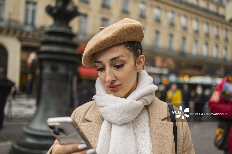 年轻女子在巴黎街头边走边看手机图片素材