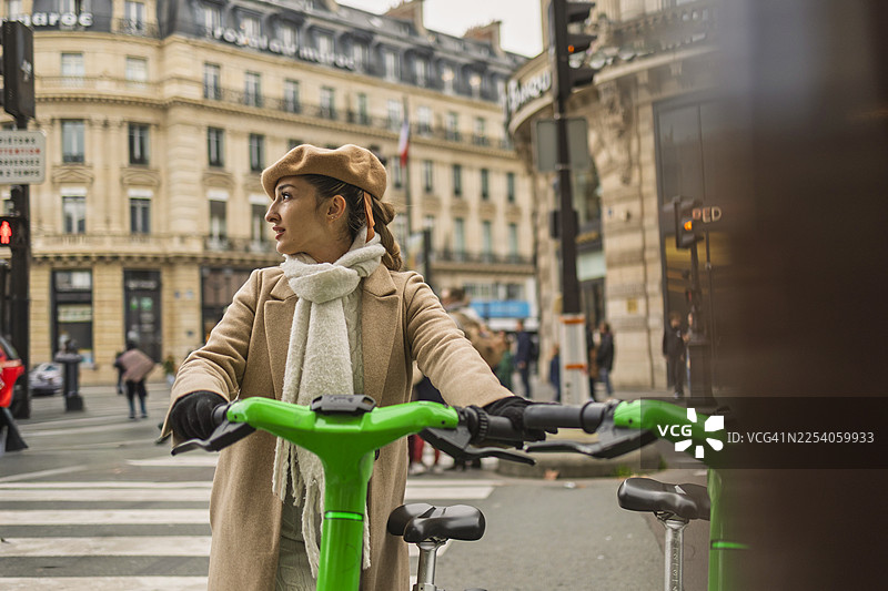 女人骑着自行车在巴黎的街道上四处张望图片素材